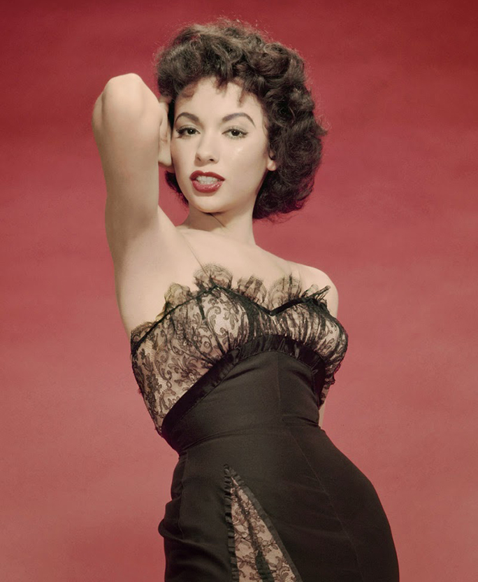 Rita Moreno  in the early 1960s in a studio photo posing with her hand in her hair