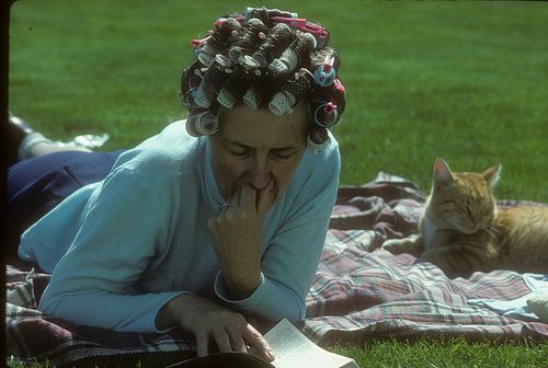 woman outside in grass wearing hair curlers with orange cat