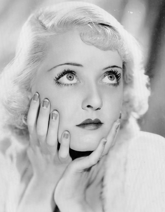Bette Davis 1930s with blond hair and hands around face with half moon manicure