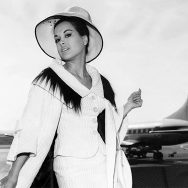 Aliza-Gur-in-movie-Contest-Girl-1964-1960s-wearing-white-suit-stanign-in-front-of-airplane